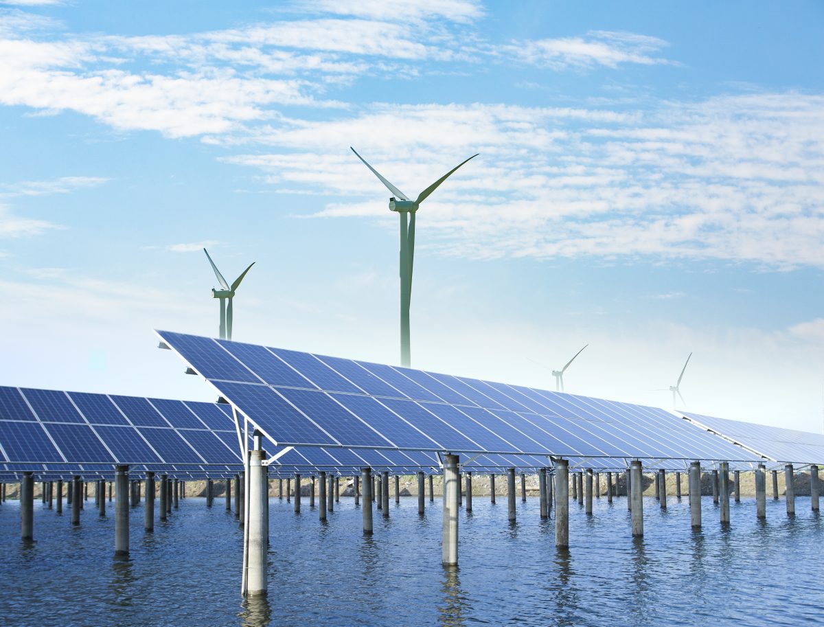 solar panels and wind turbines under blue sky on summer landscape